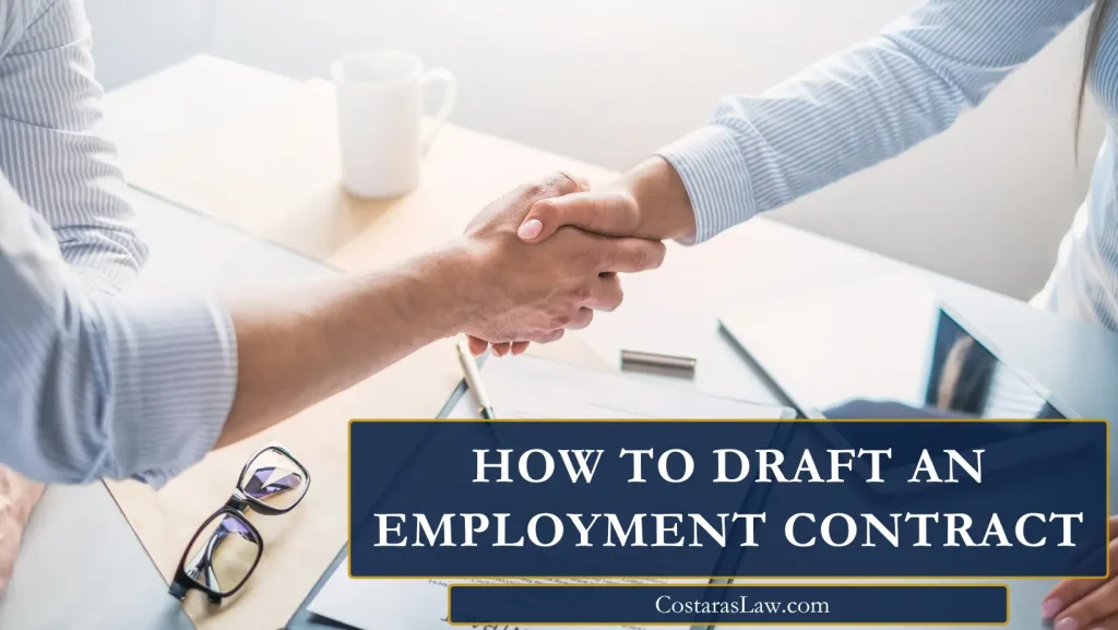 Two professionals shaking hands over a desk with documents, glasses, and a coffee cup, representing the completion of an employment contract.