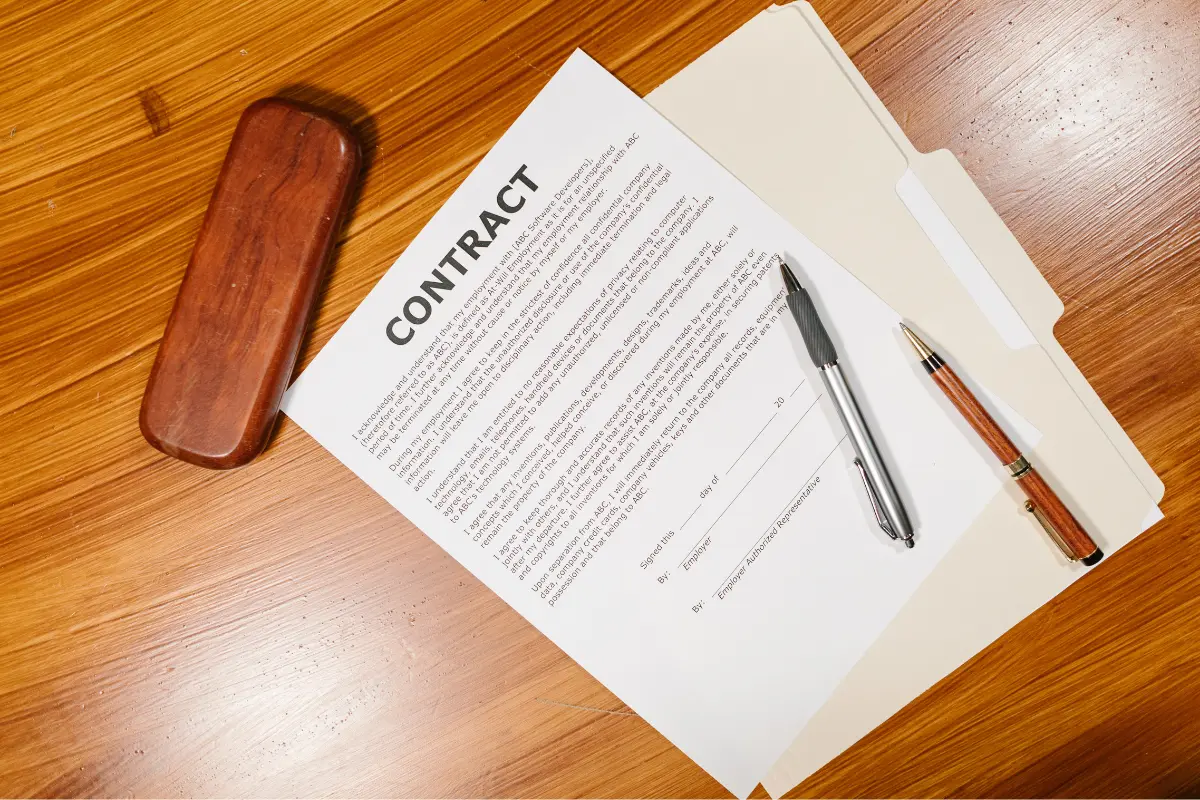 A business contract on a wooden desk with pens and a folder, highlighting Costaras Law's specialization in drafting and reviewing legal agreements.