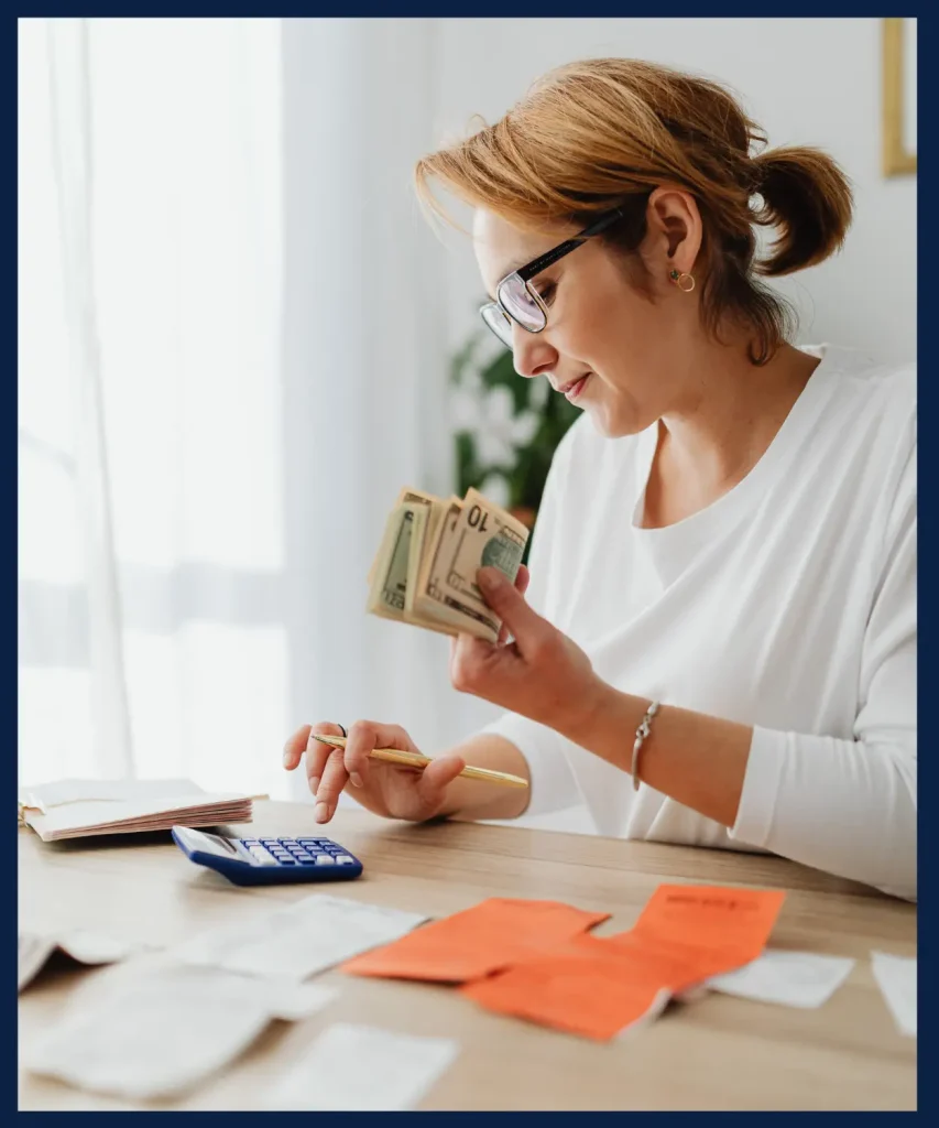 A woman counting money with receipts and a calculator on the table, illustrating Costaras Law’s support in financial management and legal guidance.